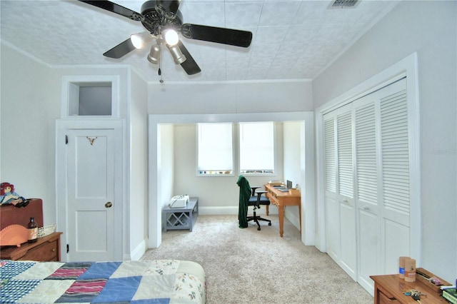 carpeted bedroom with ceiling fan, ornamental molding, and a closet