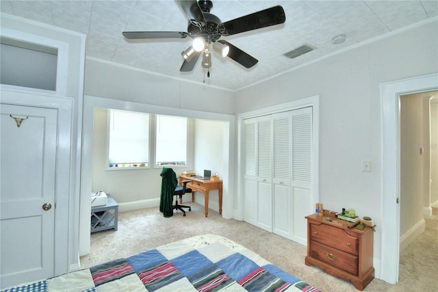 carpeted bedroom with ceiling fan, ornamental molding, and a closet