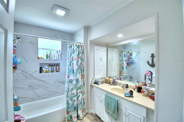 bathroom with hardwood / wood-style flooring, shower / bath combo with shower curtain, and vanity