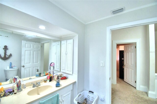 bathroom featuring toilet, vanity, and ornamental molding