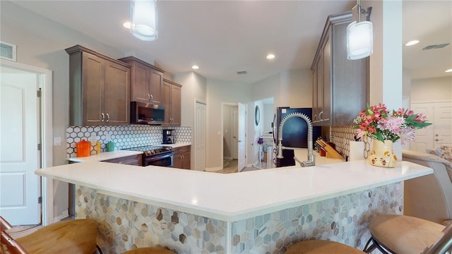 kitchen with decorative backsplash, a kitchen breakfast bar, decorative light fixtures, kitchen peninsula, and stainless steel appliances