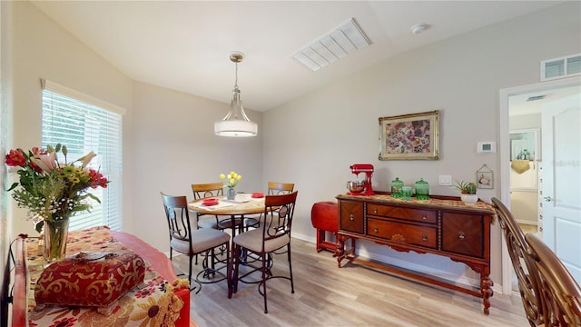 dining space with light wood-type flooring and lofted ceiling