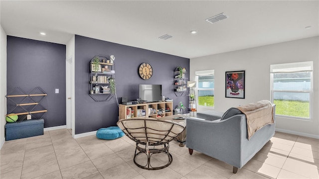 living room with light tile patterned floors, baseboards, an accent wall, and visible vents