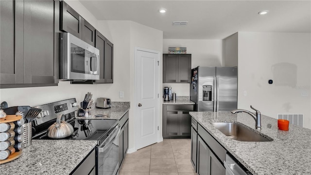 kitchen with light stone counters, stainless steel appliances, recessed lighting, visible vents, and a sink