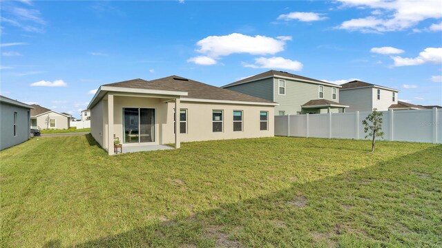 back of property with fence, a lawn, and stucco siding