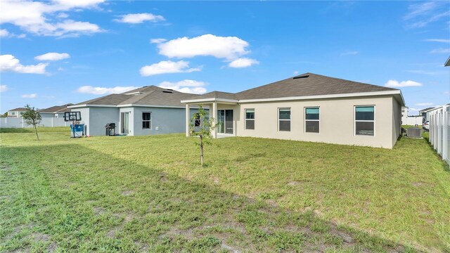 back of property featuring a yard, fence, and stucco siding