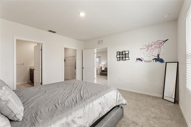 bedroom with a spacious closet, a closet, connected bathroom, and light colored carpet