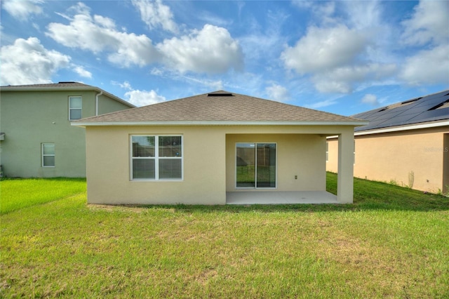 back of property with a patio area, solar panels, and a lawn