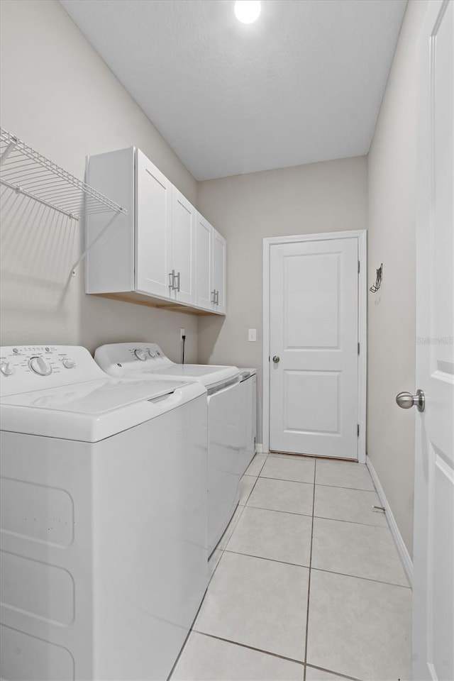 laundry area with cabinet space, light tile patterned floors, baseboards, and independent washer and dryer