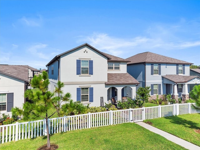 view of front facade with a fenced front yard, a front yard, and stucco siding