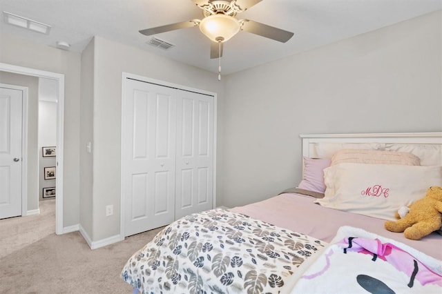 bedroom featuring light colored carpet, ceiling fan, and a closet