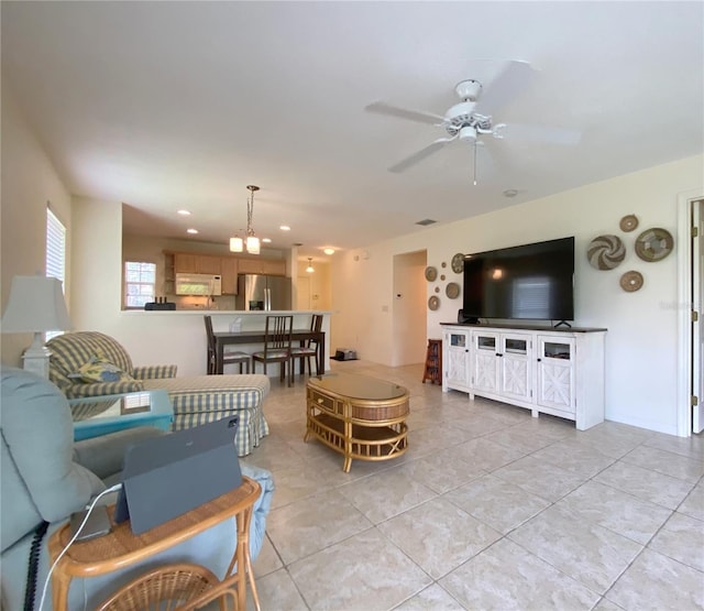 tiled living room featuring ceiling fan with notable chandelier