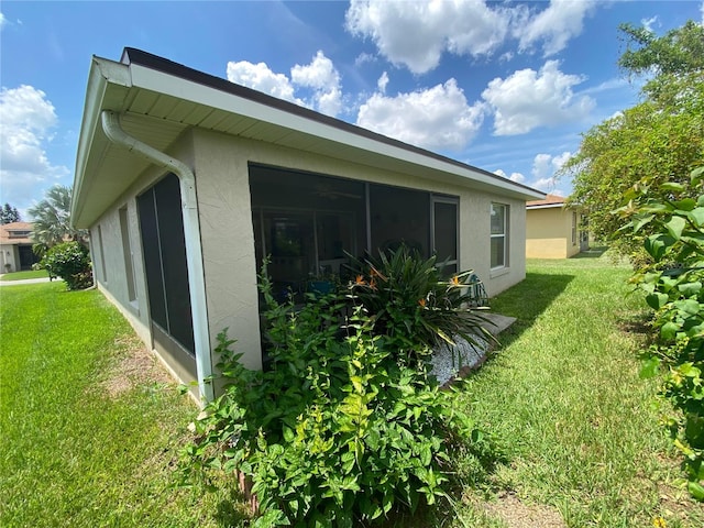 view of home's exterior with a sunroom and a yard