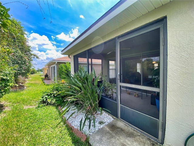 view of side of property with a sunroom and a lawn