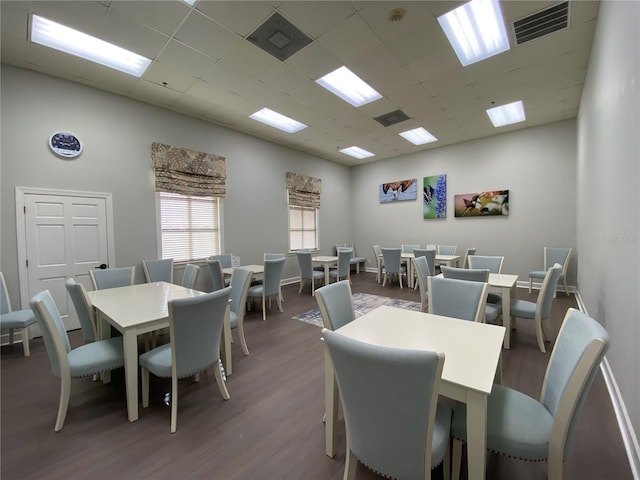 dining space with dark hardwood / wood-style flooring, a high ceiling, and a drop ceiling