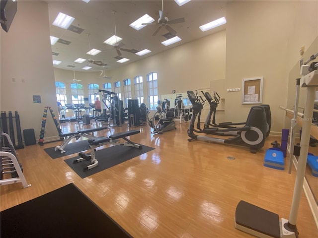 gym with ceiling fan, hardwood / wood-style flooring, and a towering ceiling