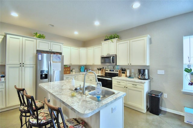 kitchen with sink, a center island with sink, a kitchen bar, and appliances with stainless steel finishes