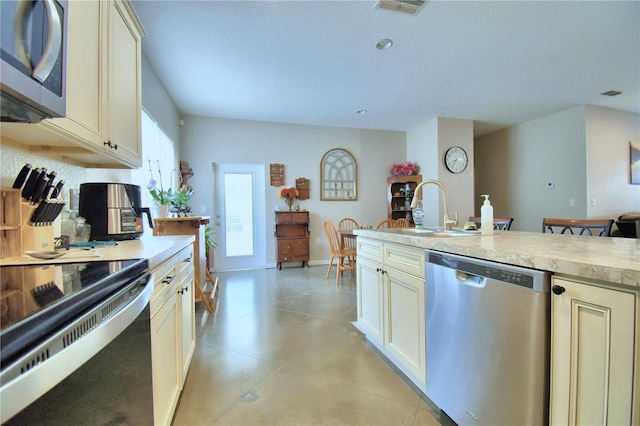 kitchen featuring a breakfast bar, cream cabinetry, sink, light tile patterned flooring, and stainless steel appliances