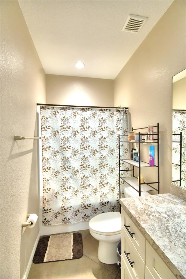 bathroom with toilet, vanity, and tile patterned floors