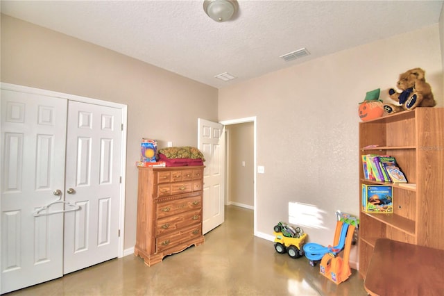 game room with a textured ceiling and concrete flooring