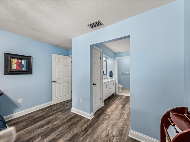 interior space with ensuite bathroom, a textured ceiling, and dark hardwood / wood-style flooring