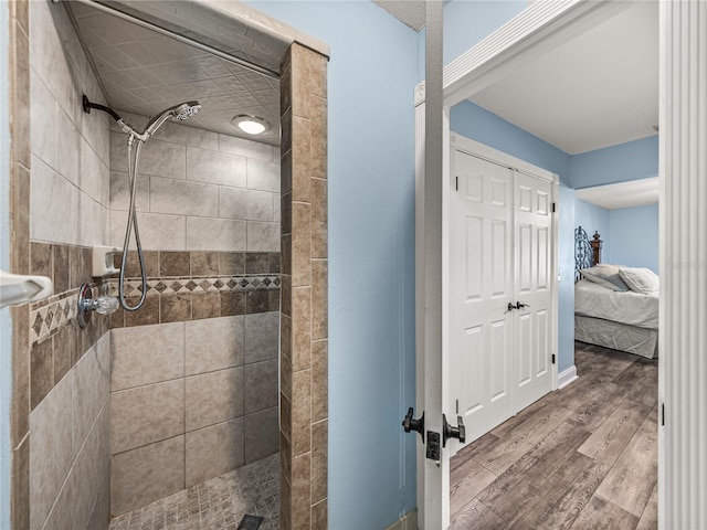 bathroom featuring a tile shower and wood-type flooring