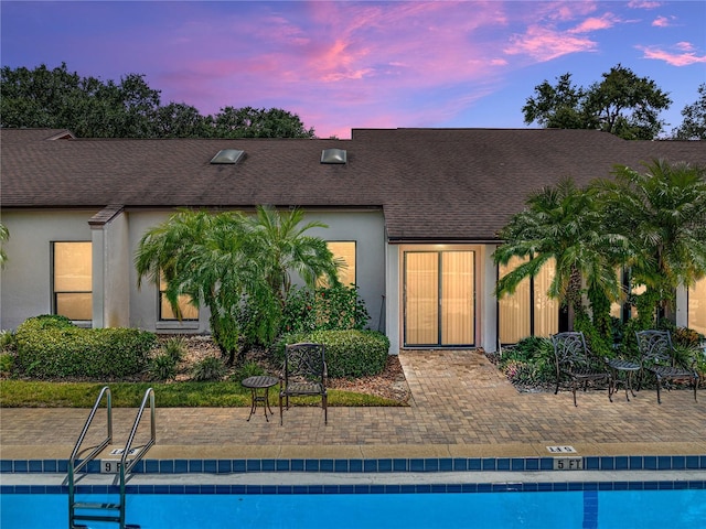 pool at dusk featuring a patio area