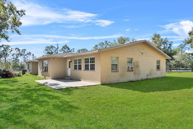 back of house featuring cooling unit, a patio area, and a lawn