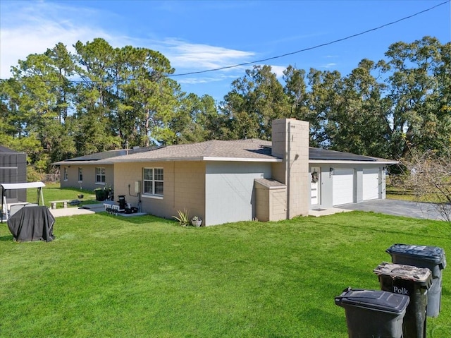 222 Rod Ln, Davenport, FL 33837 - view of side of home with a lawn, concrete block siding, driveway, a chimney, and an attached garage