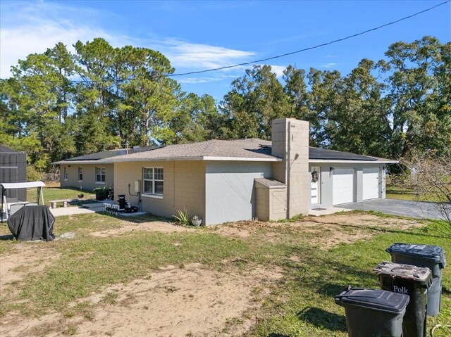 222 Rod Ln, Davenport, FL 33837 - view of property exterior featuring a yard, concrete block siding, driveway, an attached garage, and a chimney