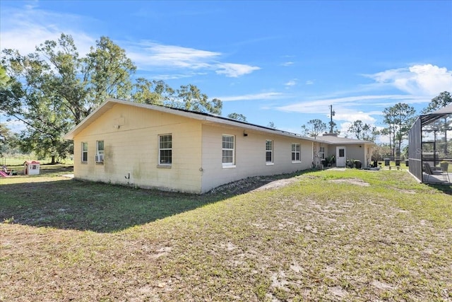 back of property with a lanai and a lawn