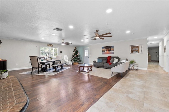 living room featuring a textured ceiling, ceiling fan, and crown molding