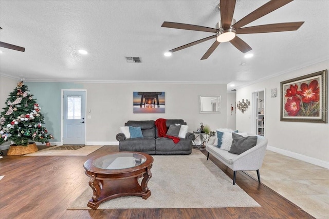 living room featuring hardwood / wood-style flooring, ceiling fan, crown molding, and a textured ceiling