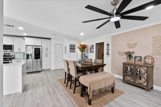 dining area featuring light hardwood / wood-style floors, a textured ceiling, and brick wall