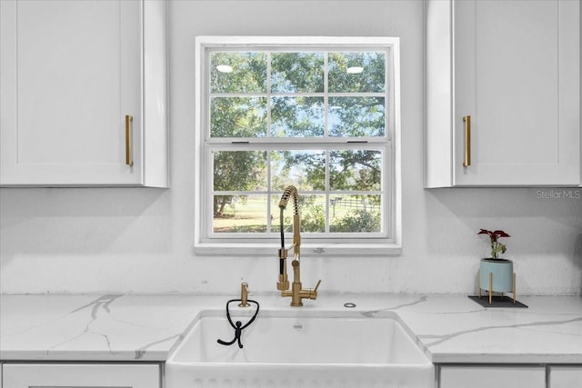 details featuring white cabinetry, light stone countertops, and sink