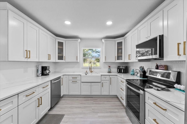 kitchen with light stone countertops, white cabinets, and stainless steel appliances