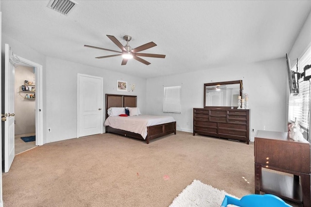 bedroom with ceiling fan, light carpet, and a textured ceiling