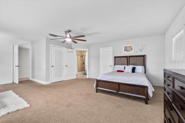 carpeted bedroom featuring a textured ceiling, ensuite bathroom, and ceiling fan