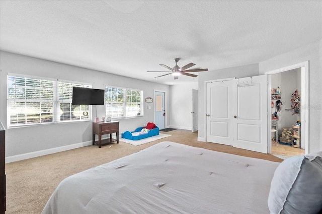 bedroom featuring ceiling fan, light colored carpet, and a textured ceiling