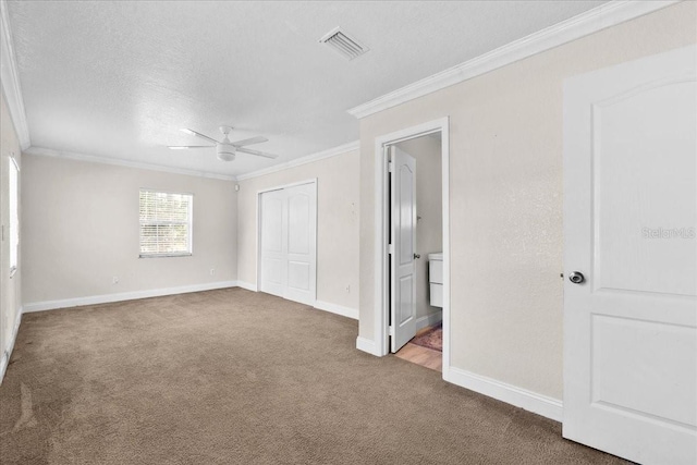 unfurnished bedroom with ceiling fan, crown molding, ensuite bathroom, carpet floors, and a textured ceiling