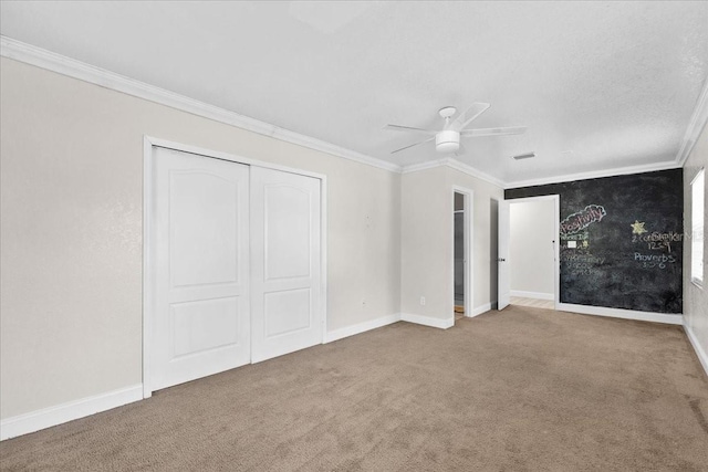 unfurnished bedroom with ceiling fan, carpet floors, crown molding, and a closet