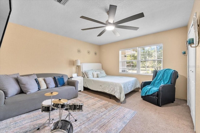 bedroom featuring a textured ceiling, light colored carpet, and ceiling fan