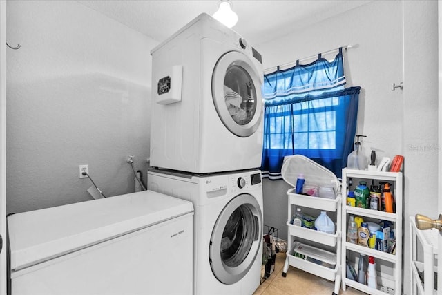 laundry room with light tile patterned floors and stacked washer / drying machine