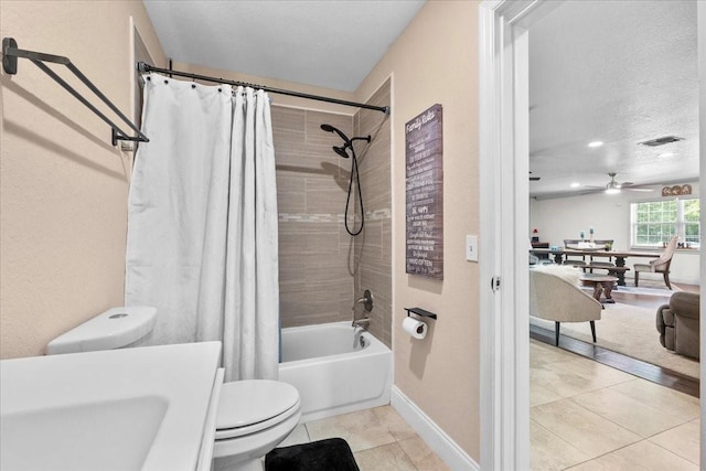 bathroom featuring ceiling fan, shower / bathtub combination with curtain, tile patterned floors, a textured ceiling, and toilet