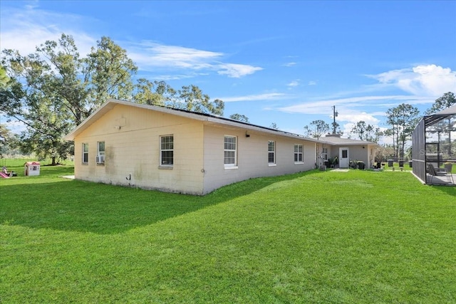 back of property with glass enclosure and a yard