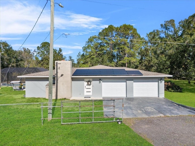 view of front of property with a garage, a front yard, and solar panels