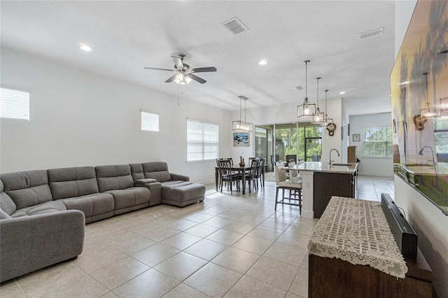 living room with sink, a textured ceiling, ceiling fan, and light tile patterned floors