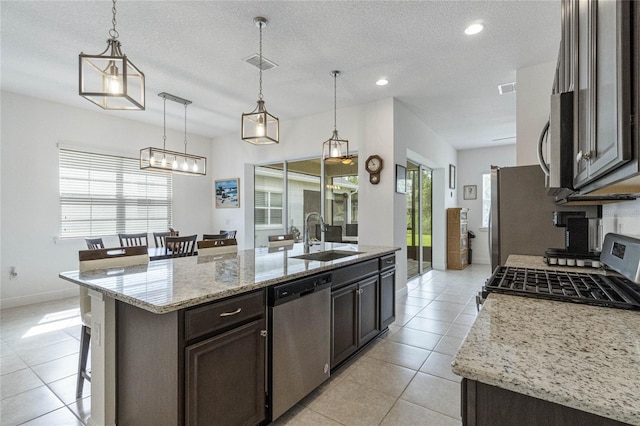 kitchen featuring sink, hanging light fixtures, an island with sink, and appliances with stainless steel finishes