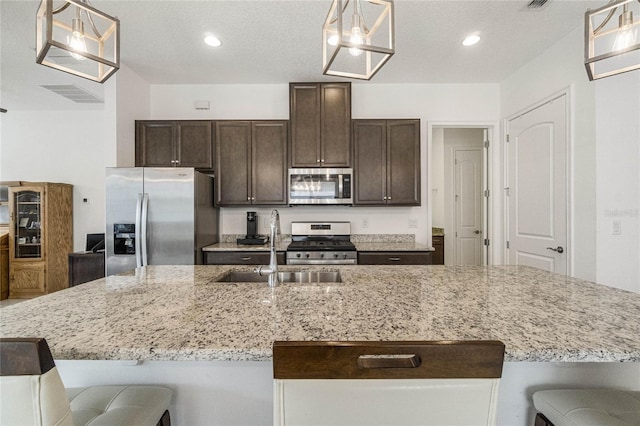 kitchen with hanging light fixtures, an island with sink, a breakfast bar area, appliances with stainless steel finishes, and sink