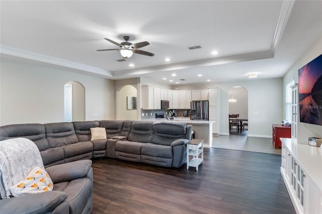 living room featuring dark hardwood / wood-style floors, ceiling fan, ornamental molding, and sink